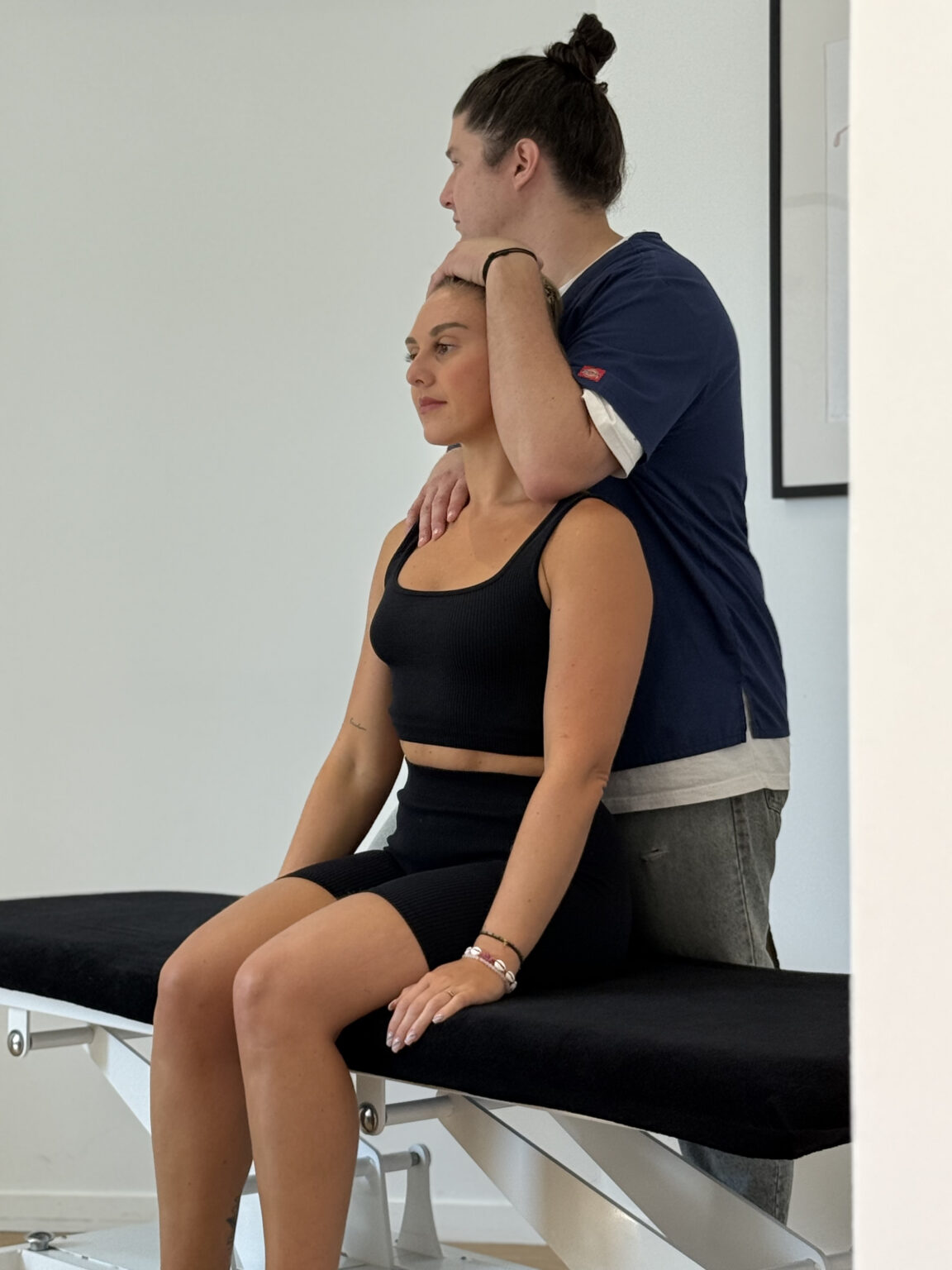 César Rostini - Ostéopathe à Toulon accompagnant une patiente assise avec un contact manuel doux et englobant sur l’épaule et la tête.